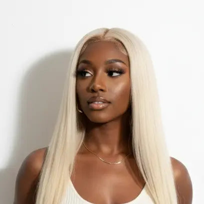 Woman wearing a white dress with a long blonde wig against a plain background