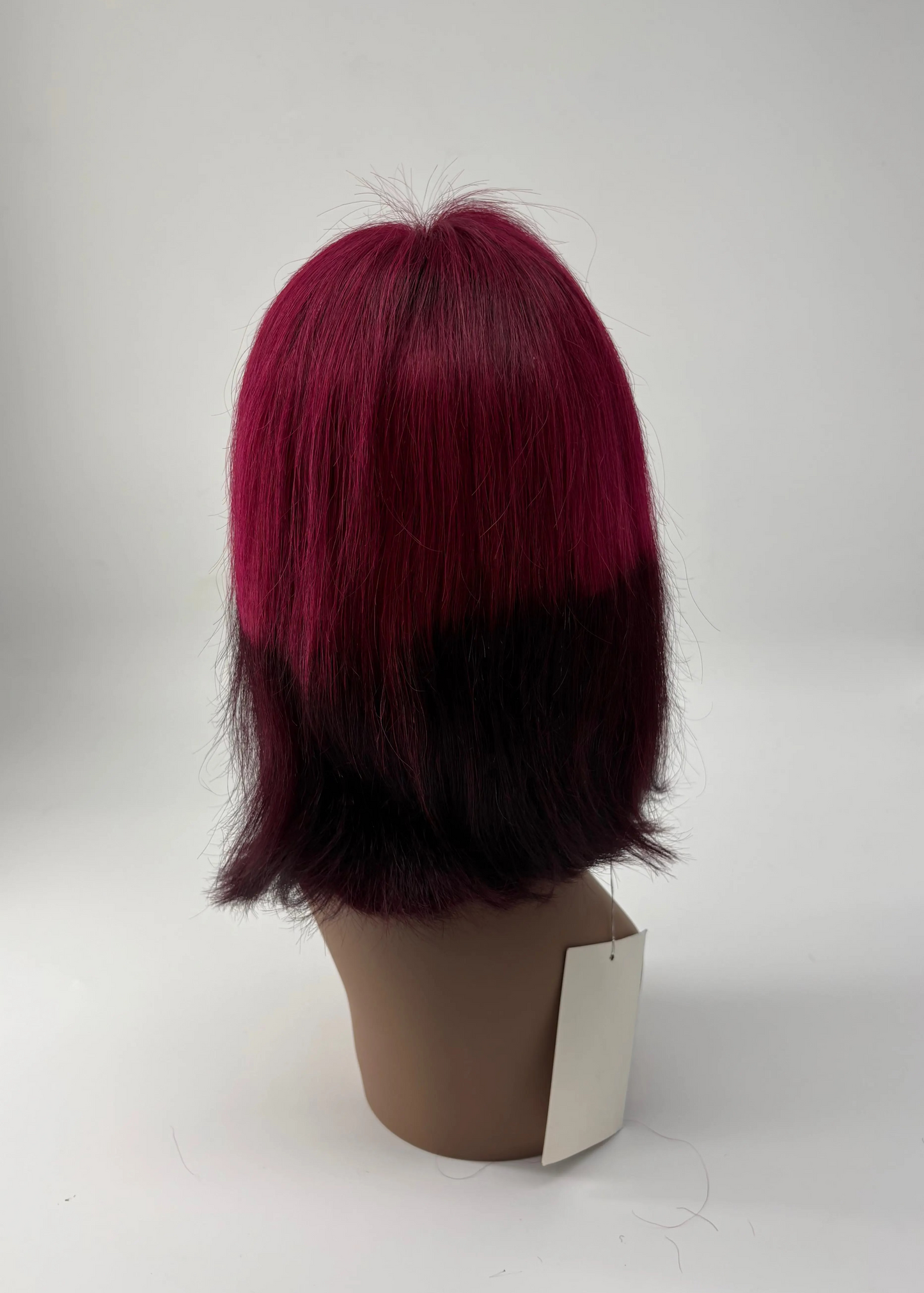 Red and black wig on a mannequin head against a white background