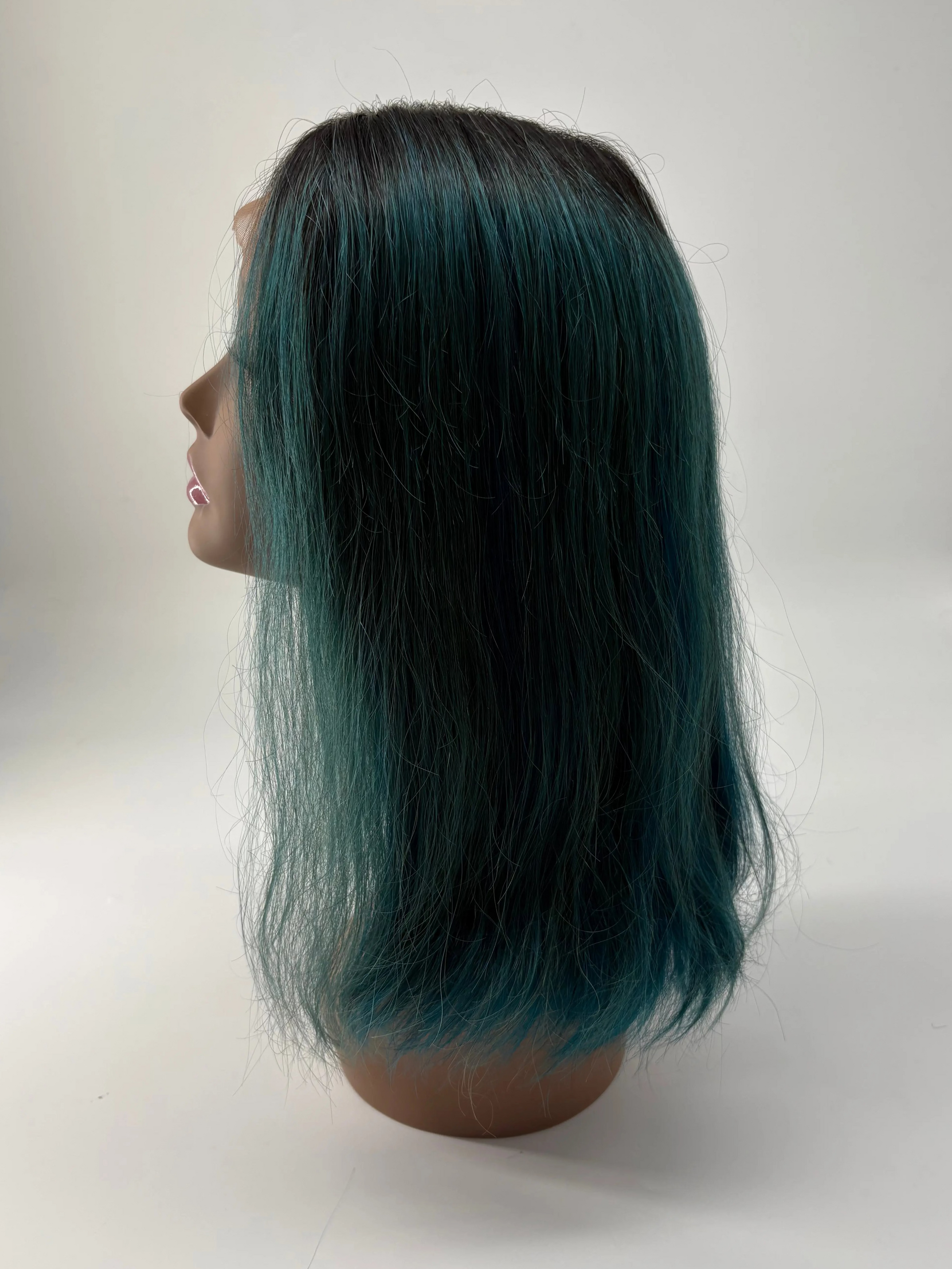 Mannequin head with teal-colored hair on a white background