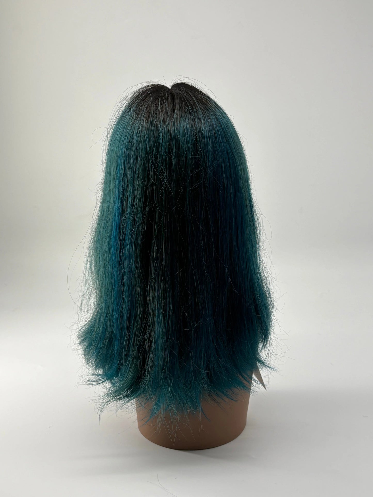 Mannequin head with teal and black hair on a white background