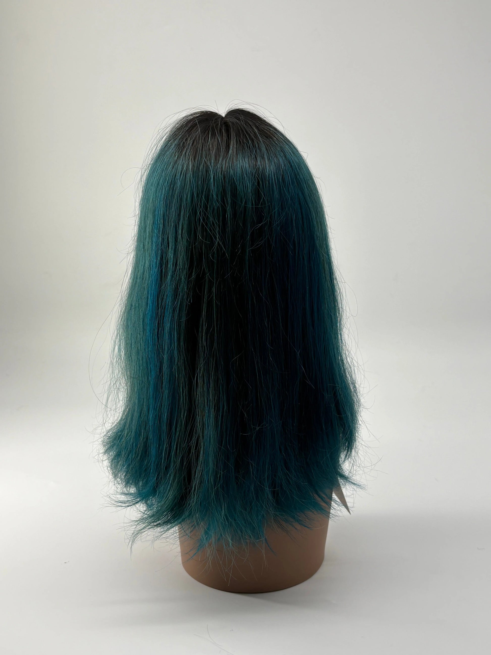 Mannequin head with teal and black hair on a white background