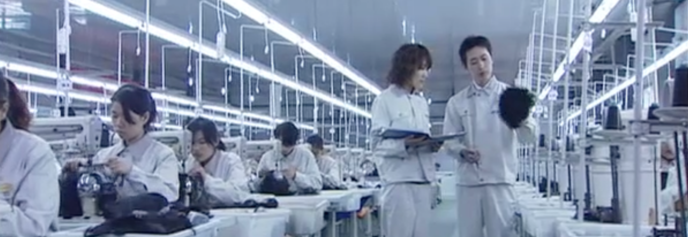 Factory workers in a line with equipment and bright lighting